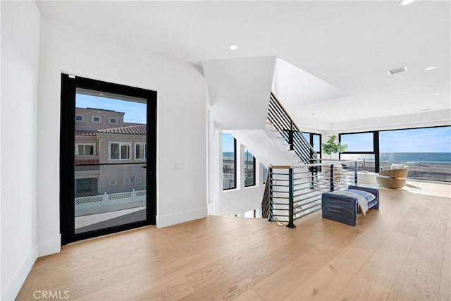 interior space with a wealth of natural light, a water view, and hardwood / wood-style flooring