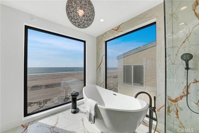 bathroom featuring a view of the beach, a water view, and a tub