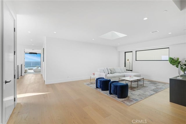 living room featuring light hardwood / wood-style floors and a skylight