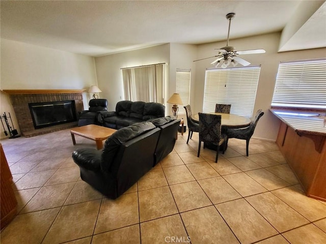 living area with ceiling fan, a brick fireplace, and light tile patterned flooring