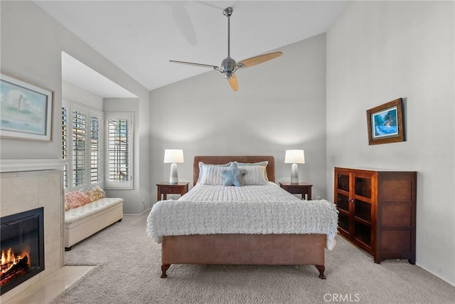 carpeted bedroom featuring high vaulted ceiling, ceiling fan, and a tiled fireplace