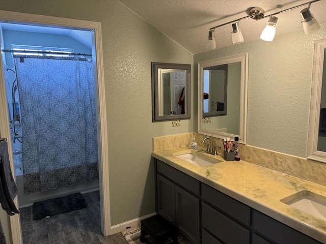 bathroom with shower / tub combo, hardwood / wood-style floors, vanity, a textured ceiling, and vaulted ceiling