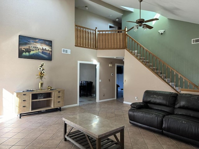 living room featuring ceiling fan, tile patterned floors, high vaulted ceiling, and a skylight