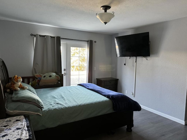 bedroom with dark wood-type flooring, access to outside, and a textured ceiling