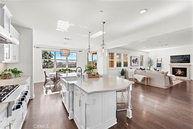 kitchen featuring white cabinets, pendant lighting, dark hardwood / wood-style flooring, and an island with sink