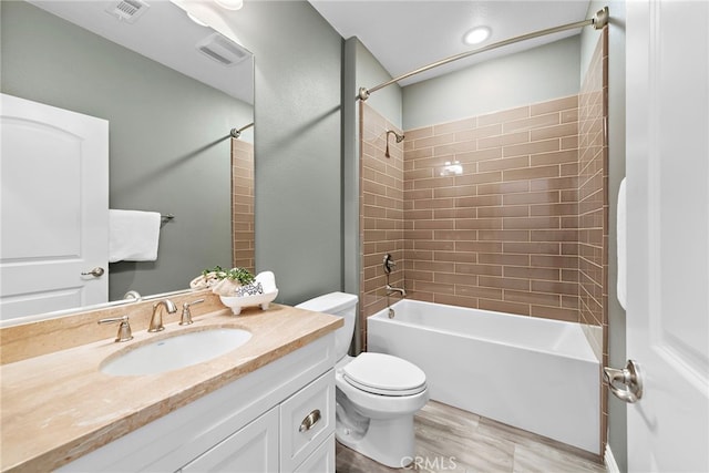 full bathroom with vanity, hardwood / wood-style flooring, toilet, and tiled shower / bath