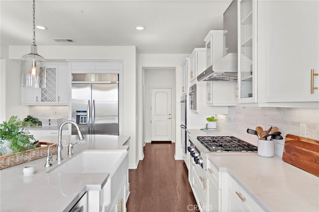 kitchen featuring dark wood-type flooring, white cabinets, decorative backsplash, appliances with stainless steel finishes, and decorative light fixtures