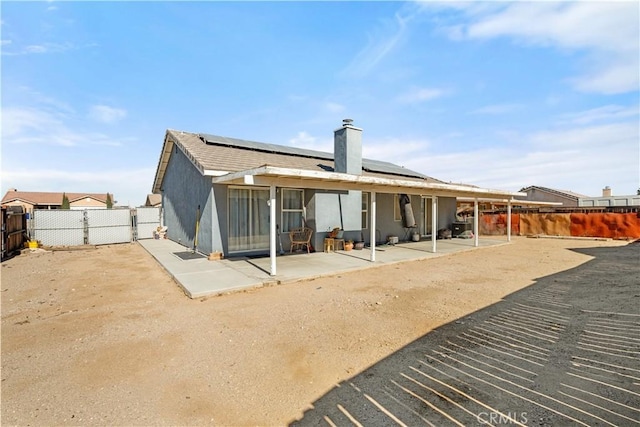 rear view of house featuring solar panels and a patio