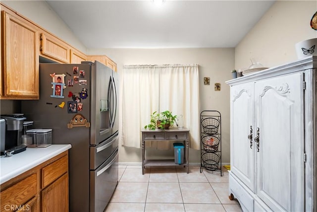 kitchen featuring stainless steel fridge, light brown cabinetry, and light tile patterned flooring