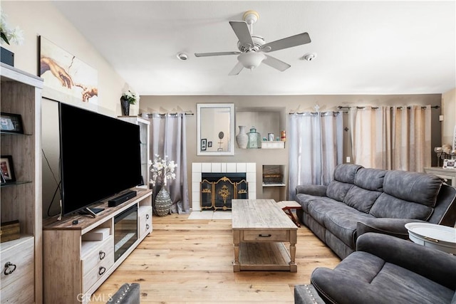 living room featuring ceiling fan, a fireplace, and light hardwood / wood-style flooring