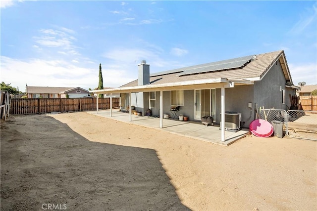 back of property with solar panels, a patio, and central AC