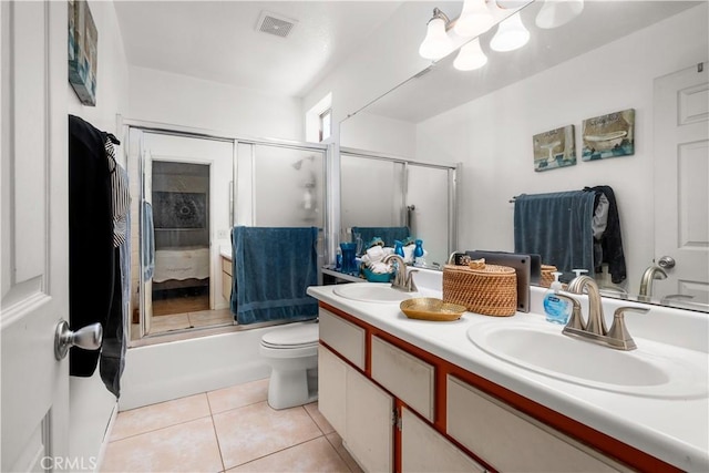 full bathroom with tile patterned flooring, vanity, combined bath / shower with glass door, and toilet