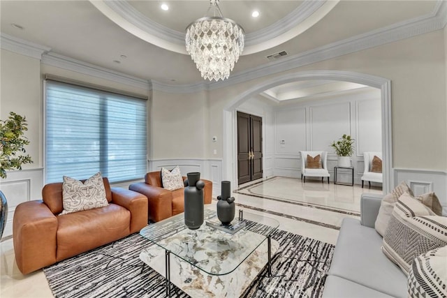 living room with an inviting chandelier, ornamental molding, and a tray ceiling