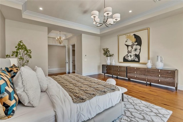 bedroom with a raised ceiling, ornamental molding, wood-type flooring, and an inviting chandelier