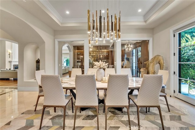 tiled dining room with a raised ceiling, ornamental molding, and a chandelier