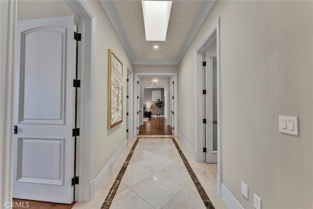 hall with ornamental molding and a skylight