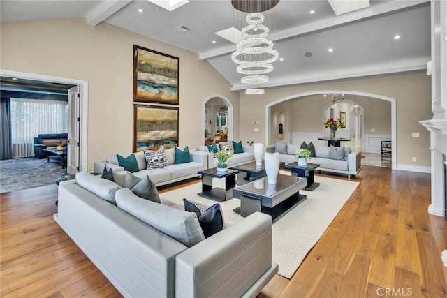 living room with a chandelier, beam ceiling, high vaulted ceiling, and light hardwood / wood-style flooring