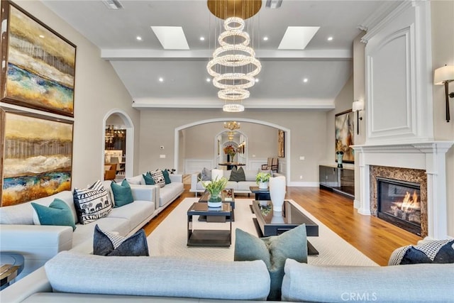 living room featuring hardwood / wood-style floors, vaulted ceiling, a high end fireplace, and an inviting chandelier