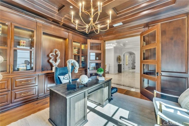 office area featuring wood walls, coffered ceiling, crown molding, a notable chandelier, and light hardwood / wood-style floors