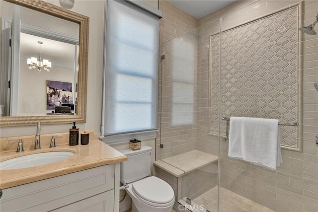 bathroom featuring toilet, vanity, an enclosed shower, and an inviting chandelier