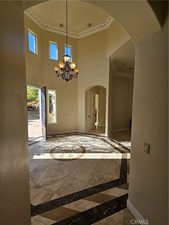 interior space with a towering ceiling, an inviting chandelier, and ornamental molding