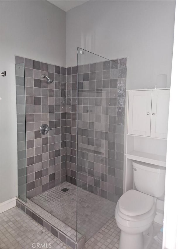 bathroom featuring a tile shower and toilet