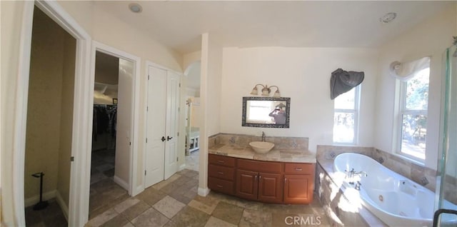 bathroom featuring a relaxing tiled tub and vanity