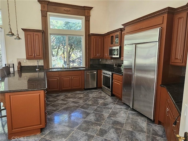 kitchen with backsplash, sink, stainless steel appliances, and hanging light fixtures