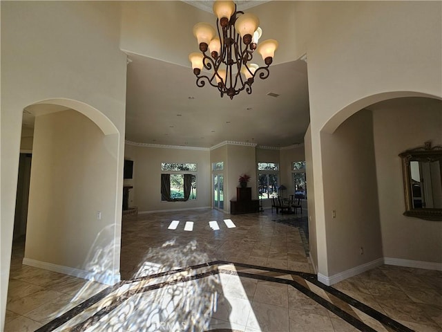 foyer with a towering ceiling, ornamental molding, and a notable chandelier