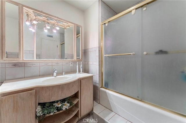 bathroom featuring tile patterned flooring, vanity, enclosed tub / shower combo, and tile walls