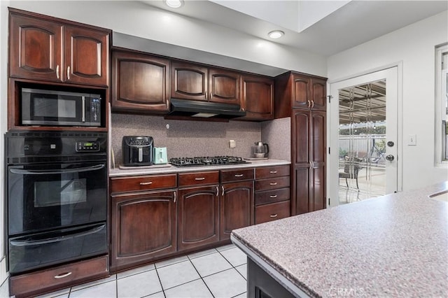 kitchen featuring gas cooktop, tasteful backsplash, dark brown cabinetry, black oven, and light tile patterned flooring