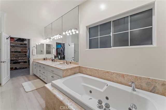 bathroom with vanity, a relaxing tiled tub, and wood-type flooring