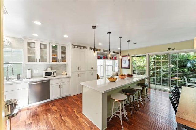 kitchen featuring sink, hanging light fixtures, white cabinets, a kitchen island, and stainless steel dishwasher