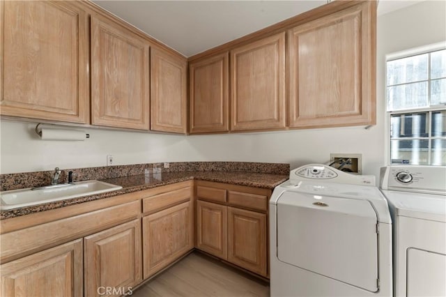 laundry room featuring cabinets, sink, washing machine and dryer, and light hardwood / wood-style flooring