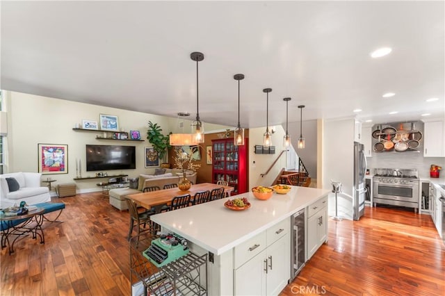 kitchen with a kitchen island, pendant lighting, white cabinets, beverage cooler, and stainless steel appliances