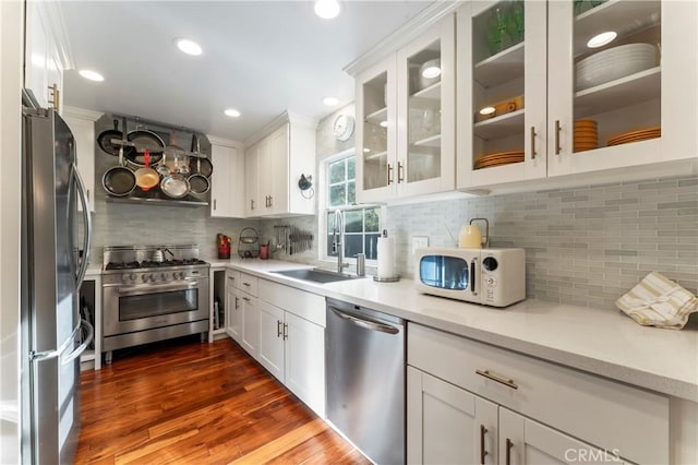 kitchen with stainless steel appliances, white cabinetry, sink, and backsplash