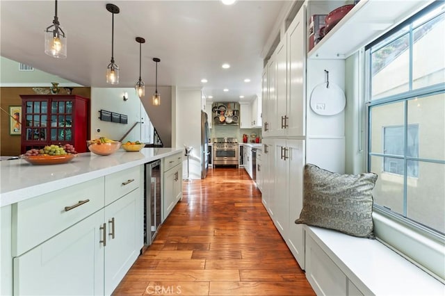 kitchen with decorative light fixtures, white cabinetry, beverage cooler, stainless steel appliances, and light wood-type flooring