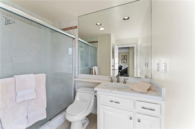 bathroom with vanity, a shower with shower door, and toilet