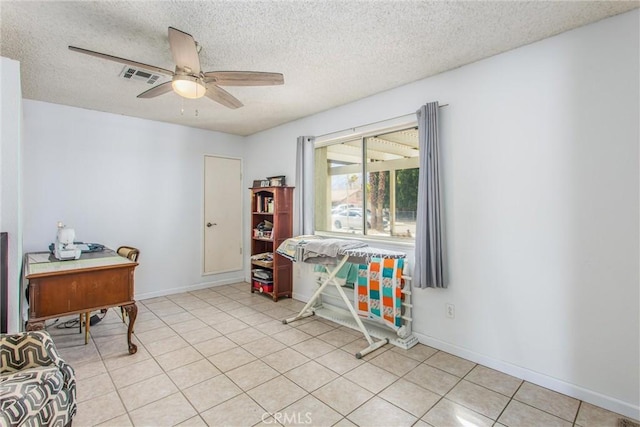 interior space with ceiling fan, a textured ceiling, and light tile patterned floors