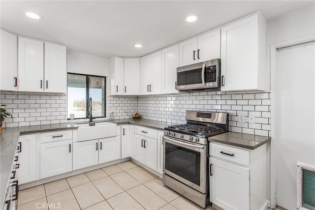 kitchen featuring light tile patterned floors, stainless steel appliances, white cabinets, and sink