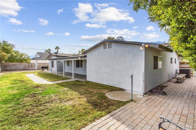 rear view of house with central AC unit, a patio area, and a lawn