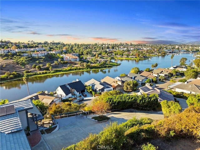 aerial view at dusk featuring a water view