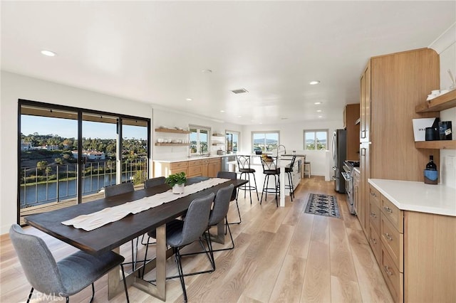 dining room with light wood-type flooring and a water view