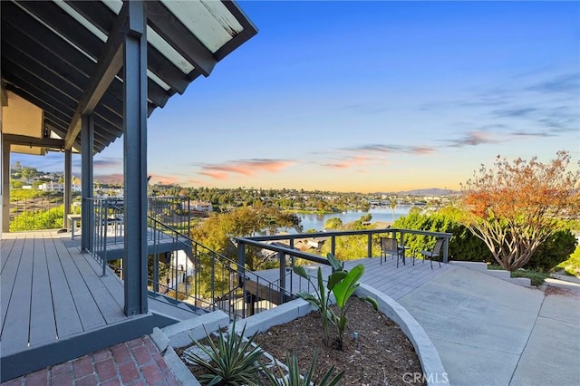 deck at dusk featuring a water view