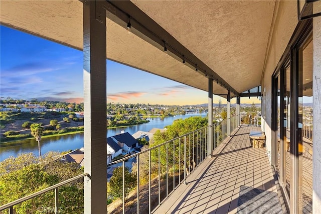 balcony at dusk featuring a water view