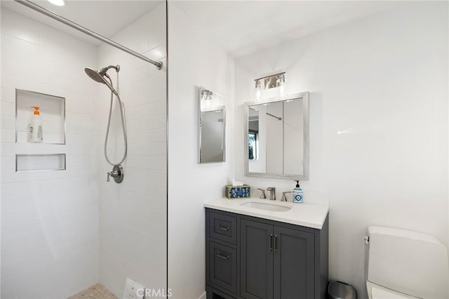 bathroom with vanity, toilet, and tiled shower