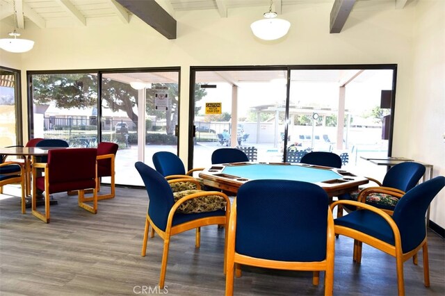 dining room with wood-type flooring, lofted ceiling with beams, and a wealth of natural light