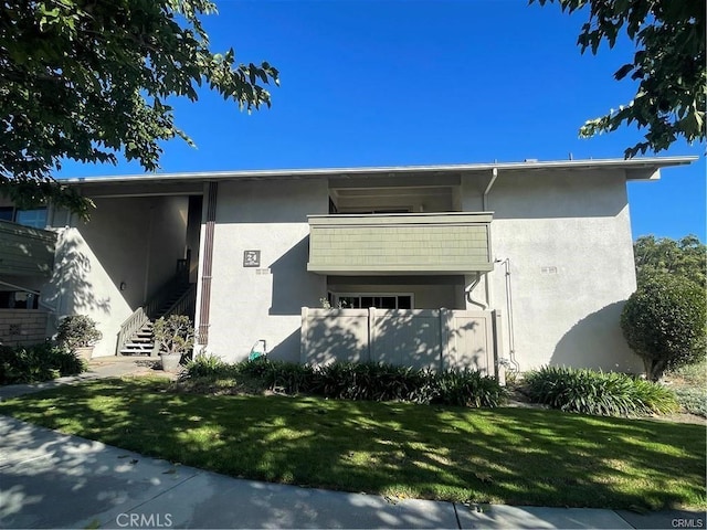 view of side of property with a balcony and a yard