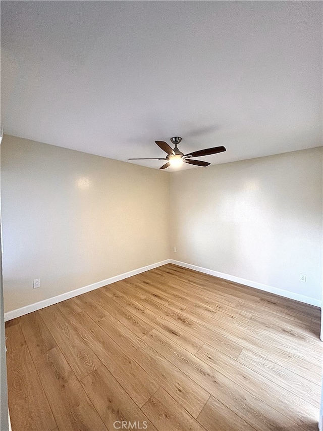 spare room with light wood-type flooring, ceiling fan, and baseboards