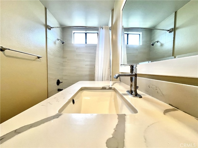 full bath with curtained shower, a healthy amount of sunlight, and vanity